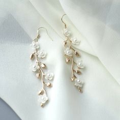 "Gold Floral Wedding earrings Gold Flower Bridal earrings Chandelier Wedding earrings Chandelier Bridal jewelry Gold Wedding jewelry These gentle bridal earrings are truly stunning and would add a romantic touch to any brides ensemble! Made from handcrafted clay flowers, 24K gold plated brass leaves they glisten and catch the light beautifully, whilst remaining classy, chic and understated. These earrings are extremely romantic! Description: - 24K Gold Plated Brass leaves - Handcrafted clay flow Floral Earrings Wedding, Flower Wedding Earrings, Bridal Gold Earrings Weddings, Delicate Gold Bridal Earrings For Wedding, Gold Delicate Bridal Earrings For Wedding, Gold Pearl Flower Earrings For Wedding, Delicate Pearl White Flower Earrings For Wedding, Gold Dangle Flower Earrings For Wedding, Delicate White Pearl Earrings For Wedding