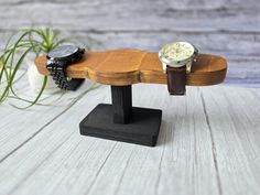 two watches are sitting on top of a wooden bench next to a potted plant