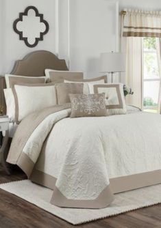 a bed with white and beige comforters in a room