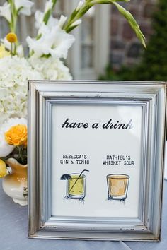 there is a sign that says have a drink and two glasses on it with flowers in the background