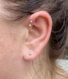 a close up of a person's ear with three small studs on it