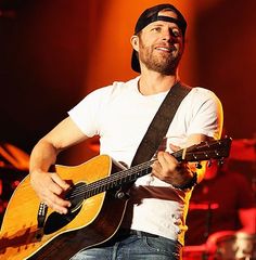 a man holding a guitar while standing on stage