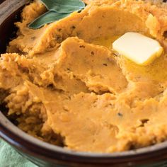 a wooden bowl filled with mashed potatoes and butter on top of a green cloth