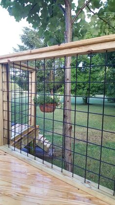 a wooden deck with a metal fence and planter in the back ground, next to a tree