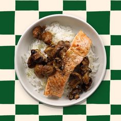 a white bowl filled with rice and meat on top of a checkered table cloth