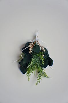 a bunch of greenery is tied up on a white surface with some gold beads