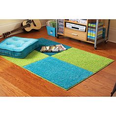 a blue and green area rug with a guitar on the floor in front of it