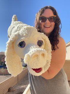 a woman holding up a knitted dog head