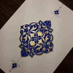 an intricate blue and gold design on white paper