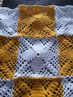 a teddy bear crocheted blanket on top of a wooden table with white and yellow squares