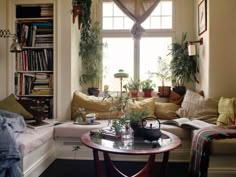 a living room filled with lots of furniture and plants on top of a window sill