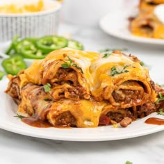 a white plate topped with enchiladas covered in cheese