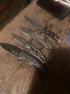 three knives sitting on top of a wooden table next to a knife sharpener and bottle opener