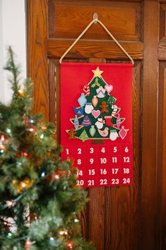 a red calendar hanging on a wooden door with a christmas tree in front of it