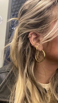 a woman with blonde hair wearing large gold hoop earrings on her ear and looking off into the distance