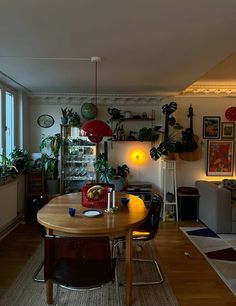 a dining room table with chairs and plants on the wall