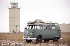 an old vw bus parked in front of a light house