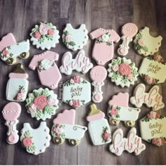 baby shower cookies decorated with pink and white icing on a wooden table next to other decorations