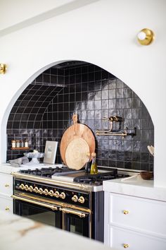 a black and white kitchen with an oven, counter top and gold trimmings