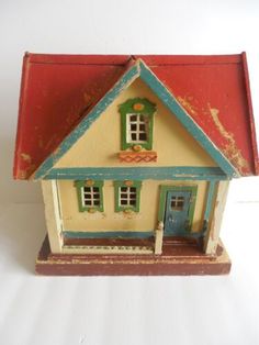 a small toy house sitting on top of a white table next to a red and blue roof