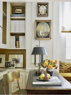 a living room filled with furniture and bookshelves next to a table topped with fruit