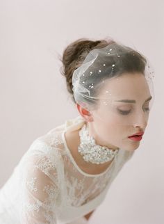 a woman wearing a veil with pearls on it