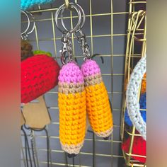 two crocheted corn cobs hanging from hooks in front of other knitted items