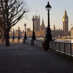 the big ben clock tower towering over the city of london from across the river thames