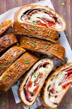 several sandwiches cut in half sitting on top of a white paper towel next to each other