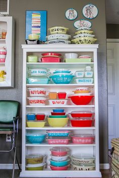 a white shelf filled with lots of colorful bowls and pans on top of it