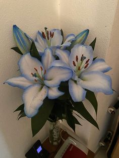 a bouquet of white lilies in a vase on a table next to a cell phone