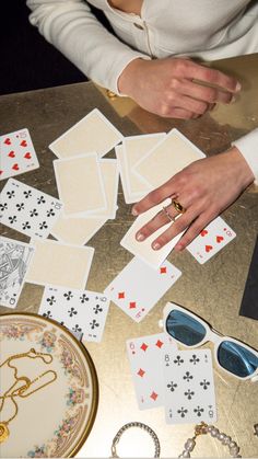 a table topped with lots of cards next to a woman's hand and sunglasses