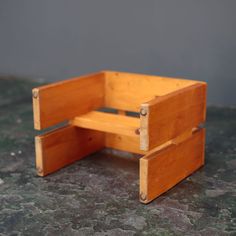 a small wooden chair sitting on top of a green table next to a gray wall