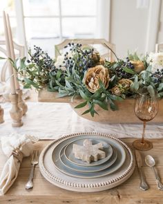 the table is set with plates, silverware and floral centerpieces on it