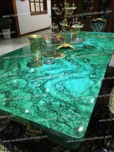 a green marble dining table with gold trimmings and glassware on the top