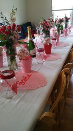 the table is set with pink and red flowers, wine bottles, and napkins