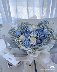 a bouquet of blue and white flowers sitting on top of a table next to a card