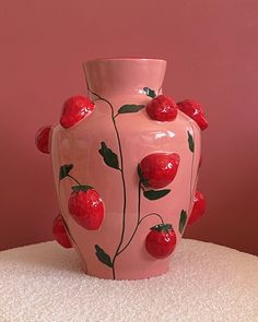 a pink vase with cherries painted on it