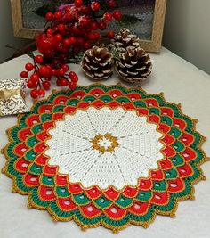 a crocheted doily sits on a table next to pine cones and berries