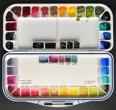 an artist's watercolor palette with its tray full of different colored paint samples