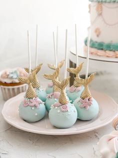 blue cake pops with gold pineapples on top and cupcakes in the background