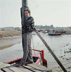 a young man standing on top of a boat in the water with skis strapped to it