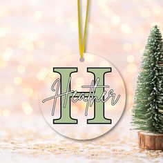 a christmas ornament with the letter h on it next to a small tree