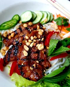 a white plate topped with meat and veggies next to sliced cucumbers