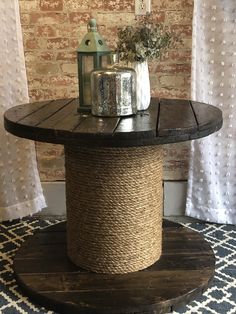 a round table with a rope wrapped around it on top of a rug in front of a brick wall