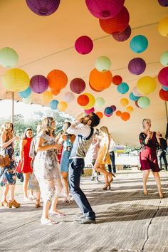 a group of people dancing under colorful paper lanterns