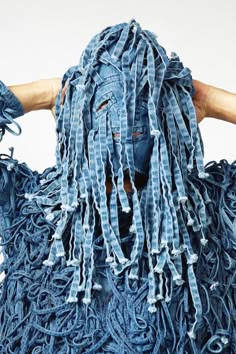 a person with long hair and dreadlocks is wearing a blue dress made out of old jeans