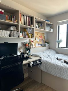 a bed sitting under a window next to a desk with a computer on top of it