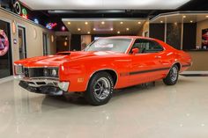 an orange muscle car parked in a showroom