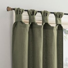 green curtains hanging on the side of a window with an open curtain rod in front of it